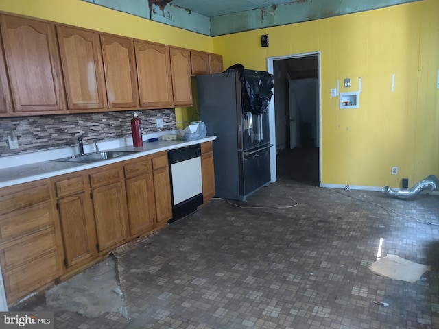 kitchen with decorative backsplash, sink, white dishwasher, and black fridge