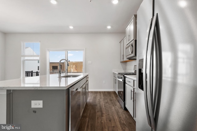 kitchen with a center island with sink, sink, dark wood-type flooring, and stainless steel appliances