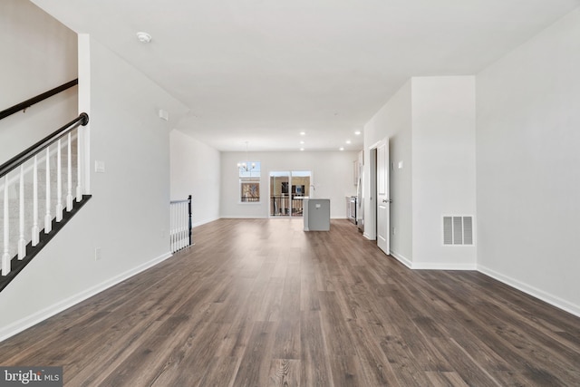 unfurnished living room featuring a notable chandelier and dark hardwood / wood-style floors