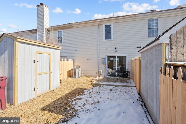 rear view of house featuring central air condition unit and a storage shed