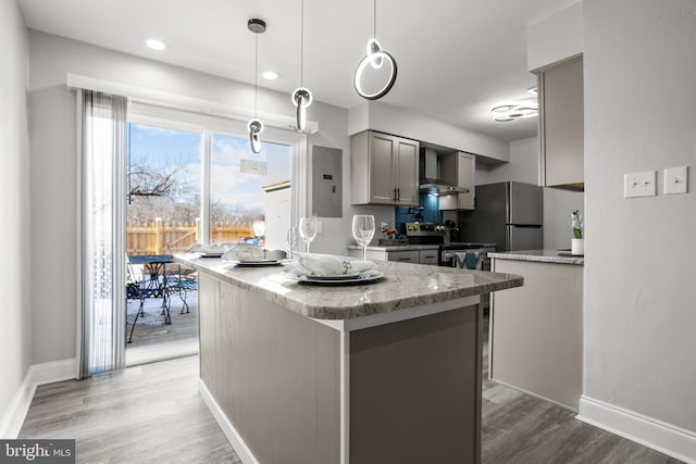 kitchen featuring wall chimney exhaust hood, gray cabinetry, wood-type flooring, hanging light fixtures, and stainless steel appliances