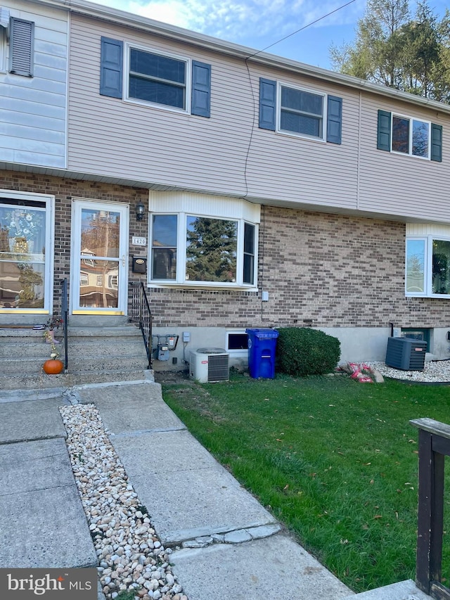 townhome / multi-family property with central air condition unit and a front yard