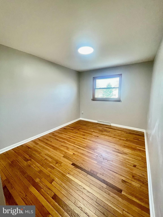 unfurnished room featuring hardwood / wood-style floors and baseboard heating