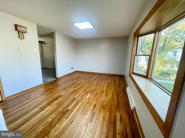 unfurnished room featuring hardwood / wood-style flooring and baseboard heating