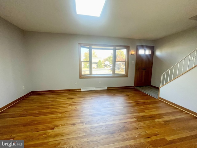 foyer featuring a baseboard heating unit, light hardwood / wood-style floors, and a skylight