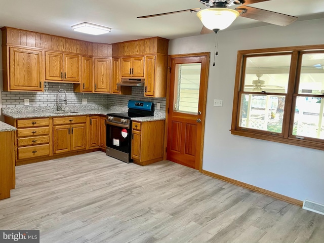 kitchen featuring stainless steel electric stove, tasteful backsplash, sink, and light stone countertops