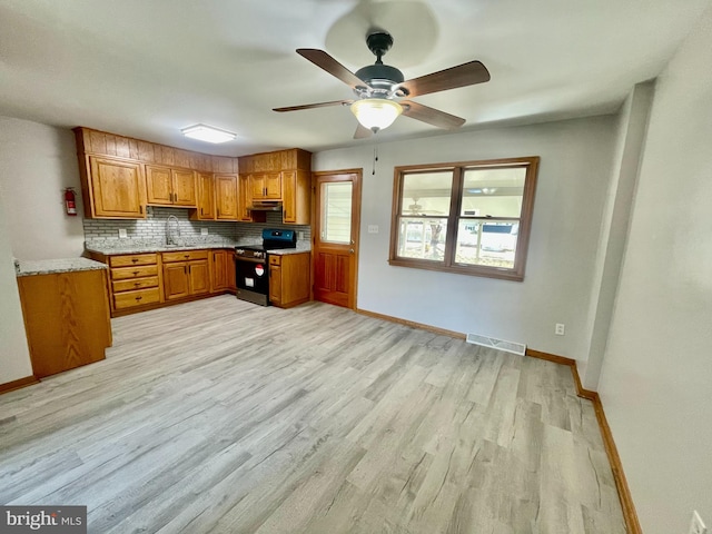 kitchen featuring plenty of natural light, backsplash, sink, and black range oven