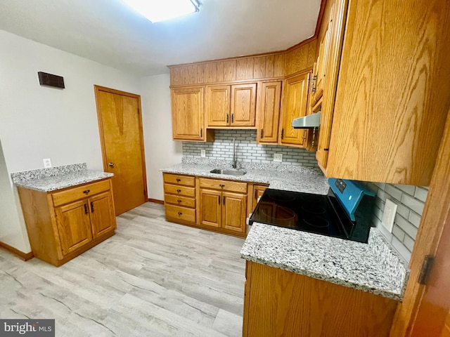 kitchen with tasteful backsplash, exhaust hood, black stove, light hardwood / wood-style flooring, and sink