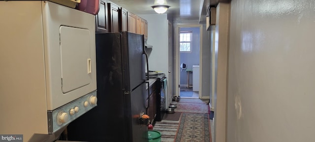 kitchen with black appliances and stacked washer / drying machine