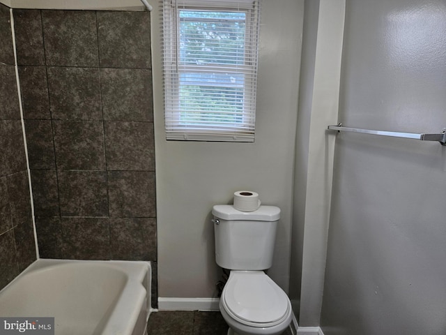 bathroom featuring tiled shower / bath, toilet, and tile patterned flooring