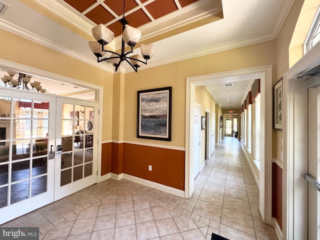 interior space with plenty of natural light, an inviting chandelier, french doors, and ornamental molding