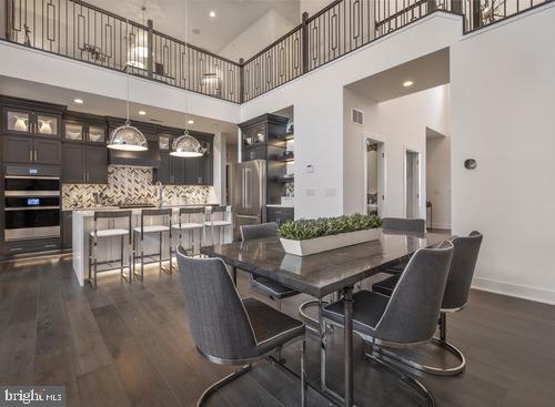 dining area with dark wood-type flooring and a towering ceiling