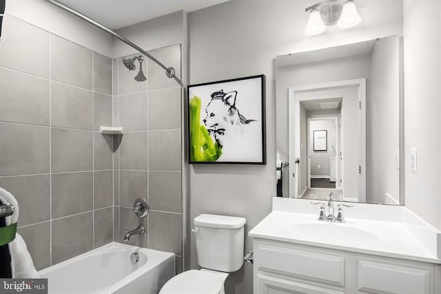 full bathroom featuring vanity, tiled shower / bath combo, and toilet