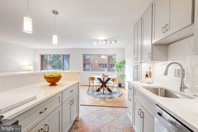 kitchen featuring light hardwood / wood-style flooring, hanging light fixtures, sink, stainless steel dishwasher, and white cabinets