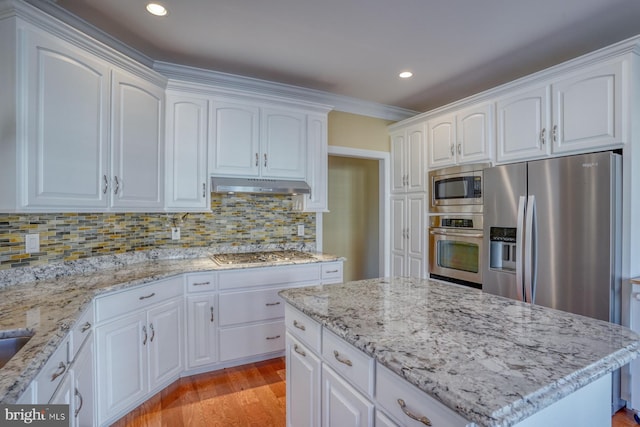 kitchen featuring white cabinets, tasteful backsplash, appliances with stainless steel finishes, light stone countertops, and light wood-type flooring