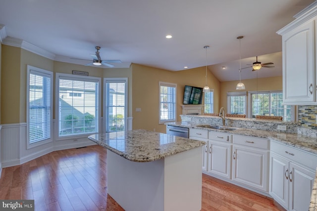 kitchen with a healthy amount of sunlight, dishwasher, a kitchen island, and white cabinets