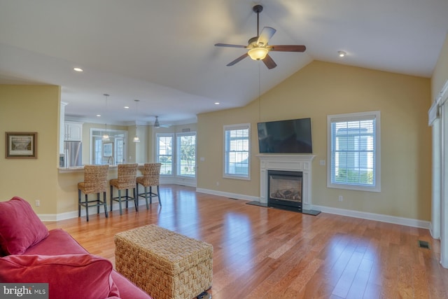 living room with light hardwood / wood-style floors, vaulted ceiling, and ceiling fan