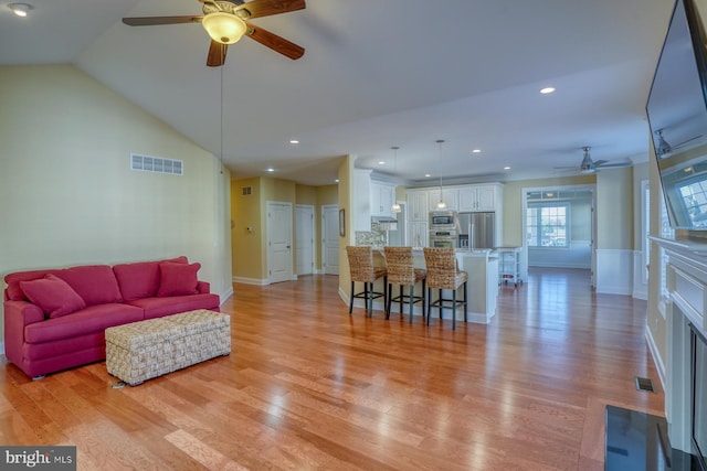 living room with ceiling fan, lofted ceiling, and light wood-type flooring