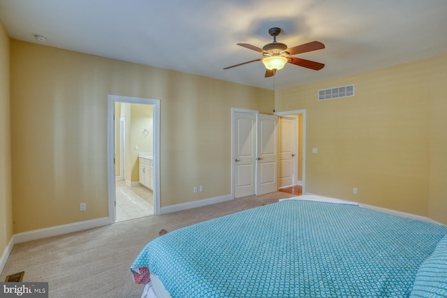 carpeted bedroom with ensuite bathroom and ceiling fan