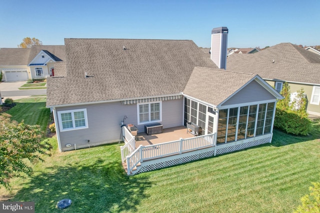 rear view of property with a wooden deck, a yard, and a sunroom