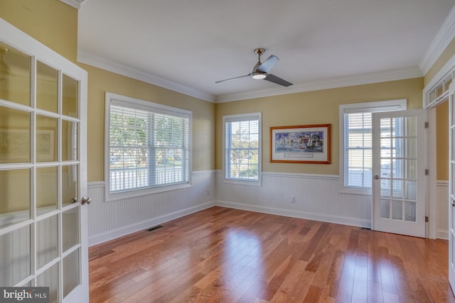 spare room featuring french doors, light hardwood / wood-style floors, and a healthy amount of sunlight