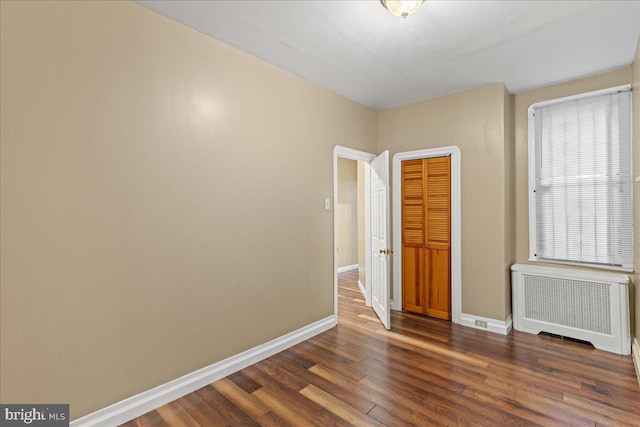 empty room featuring radiator heating unit and dark hardwood / wood-style floors