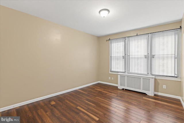 unfurnished room featuring radiator heating unit, dark hardwood / wood-style floors, and plenty of natural light