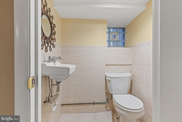 bathroom featuring toilet, sink, tile walls, and tile patterned flooring