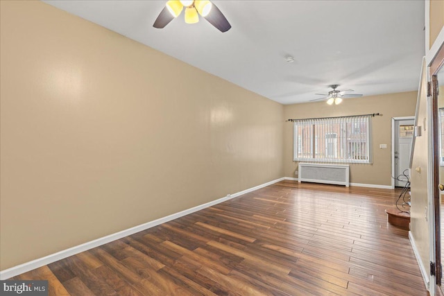 spare room featuring dark wood-type flooring, ceiling fan, and radiator