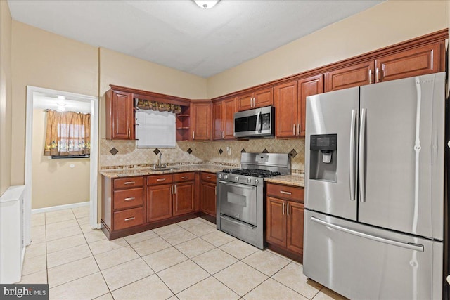 kitchen featuring light stone counters, stainless steel appliances, sink, and backsplash