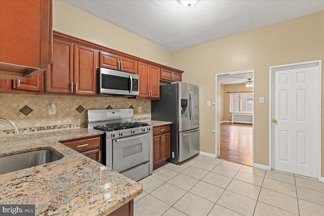 kitchen featuring appliances with stainless steel finishes, light tile patterned flooring, light stone countertops, and sink