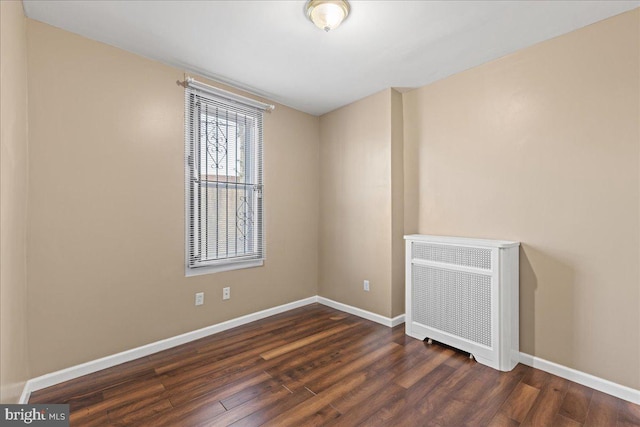 empty room with radiator heating unit and dark hardwood / wood-style floors