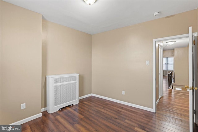 empty room featuring dark hardwood / wood-style flooring and radiator heating unit