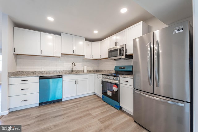 kitchen with white cabinets, backsplash, light hardwood / wood-style flooring, sink, and stainless steel appliances