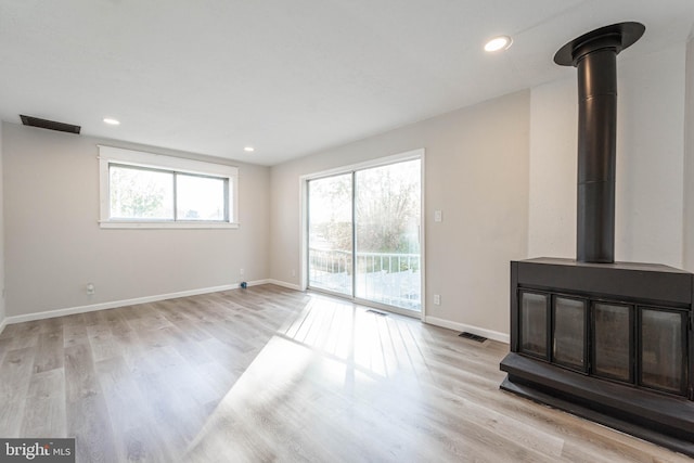 unfurnished living room with light hardwood / wood-style floors and a wood stove