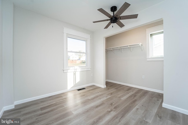 unfurnished bedroom with light hardwood / wood-style flooring, multiple windows, a closet, and ceiling fan