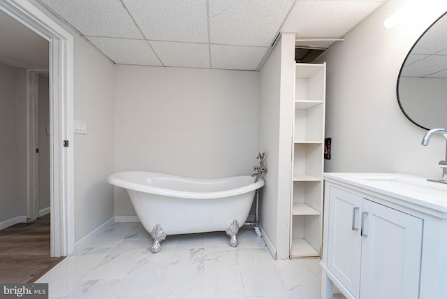 bathroom with vanity, a drop ceiling, and a tub