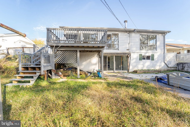 rear view of house with a wooden deck and a lawn