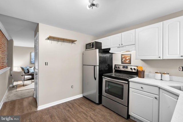 kitchen featuring white cabinetry, stainless steel appliances, dark wood-type flooring, and brick wall