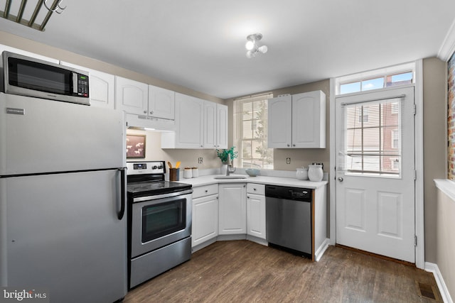 kitchen featuring appliances with stainless steel finishes, sink, dark hardwood / wood-style floors, and white cabinets