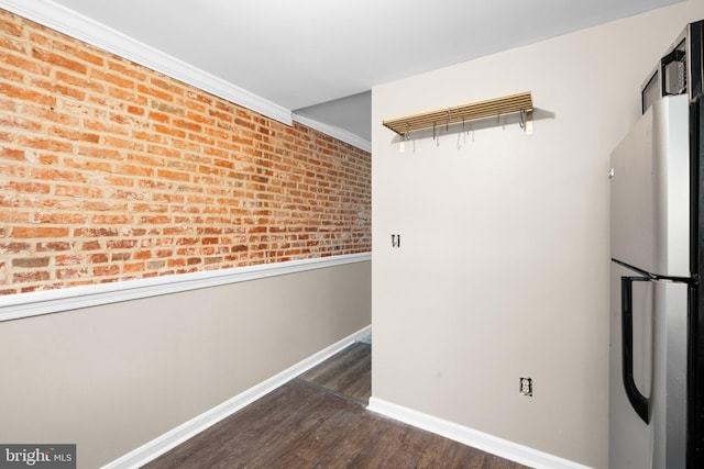 interior space featuring brick wall, stainless steel refrigerator, ornamental molding, and dark hardwood / wood-style floors