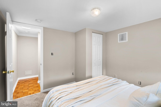 bedroom featuring crown molding, light parquet floors, and a closet