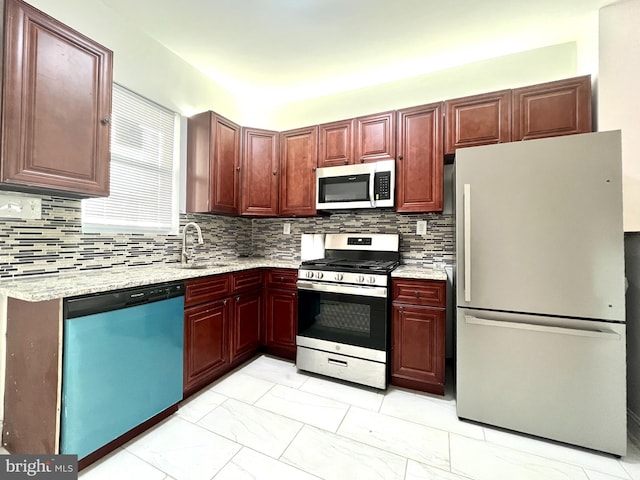 kitchen with stainless steel appliances, light stone counters, sink, and tasteful backsplash