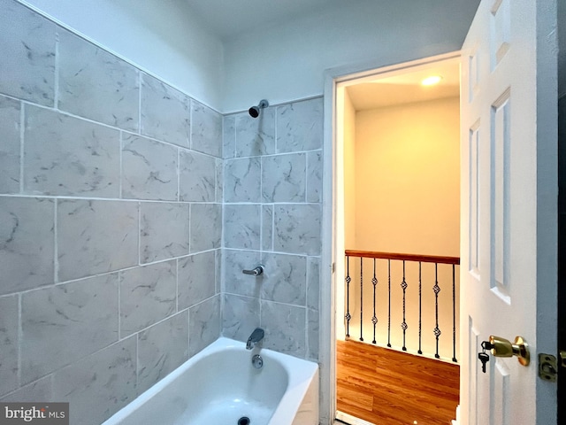 bathroom with hardwood / wood-style floors and tiled shower / bath