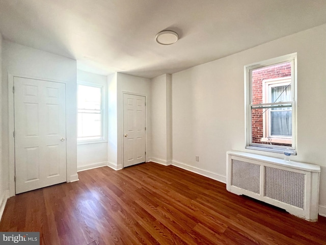 unfurnished room featuring radiator heating unit and dark hardwood / wood-style flooring