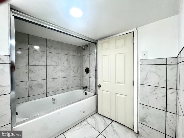 bathroom featuring tiled shower / bath and tile walls