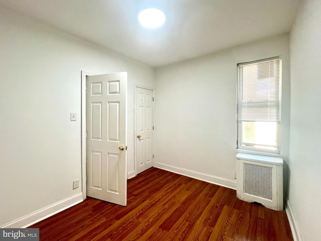 unfurnished room with dark hardwood / wood-style flooring and radiator