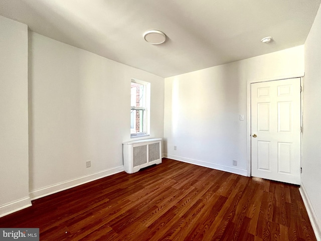 unfurnished room featuring radiator heating unit and dark wood-type flooring