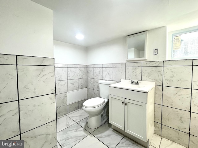 bathroom with vanity, toilet, and tile walls