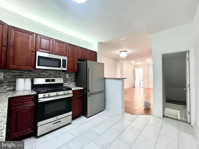 kitchen featuring appliances with stainless steel finishes, light hardwood / wood-style floors, light stone counters, and backsplash